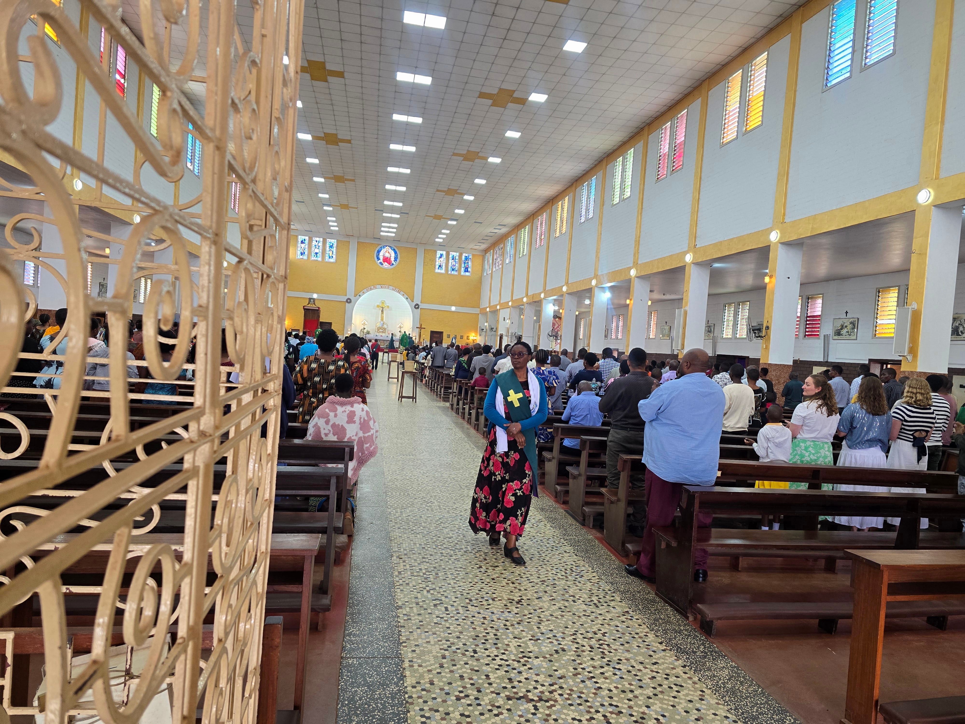 Wide-angle interior view showing the main aisle, high ceiling, and seating hall inside Christ the King Cathedral.