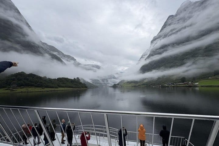 Cruise passengers viewing misty Nærøyfjord from the open deck