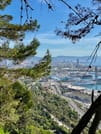 Panoramic view from top of Montjuic hill overlooking the old harbour of Barcelona. You can see the ocean and a mountain range in the back.