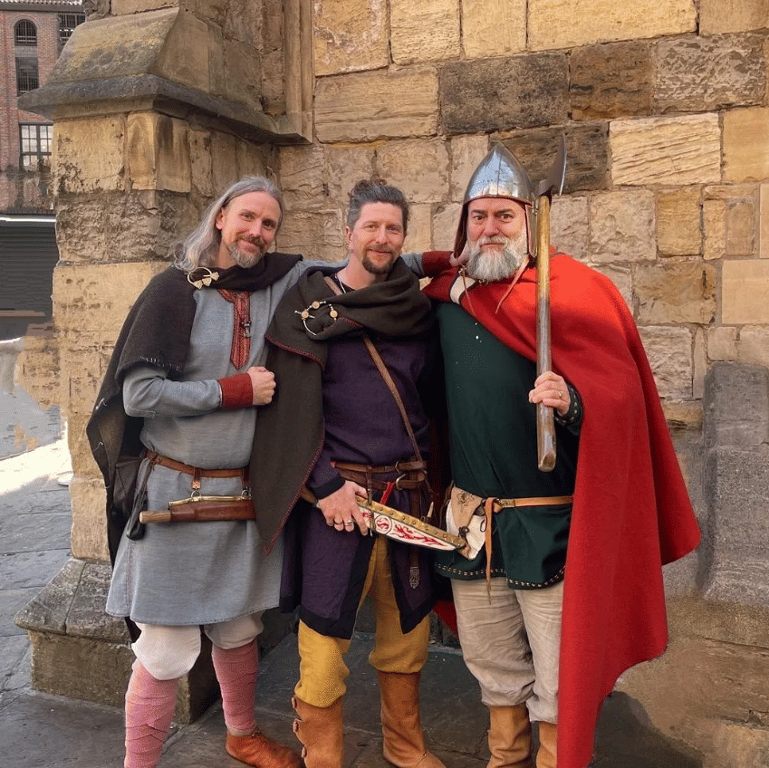 Three viking men stood in front of Saint Mary's Church, Coppergate, York