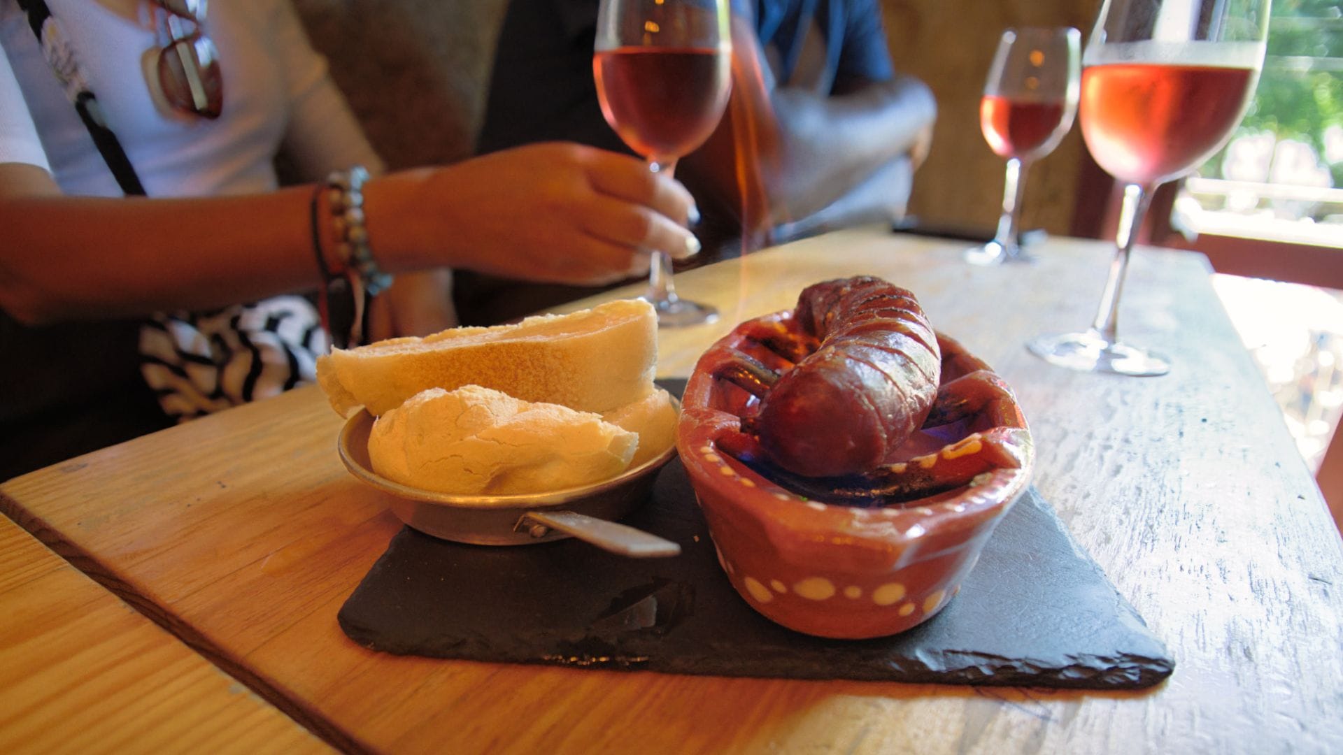 Traditional flaming chorizo served with bread and rosé wine at a Porto wine bar