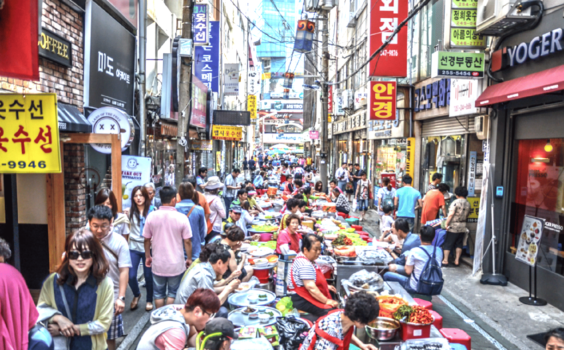 A crowded alley lined with vendor stalls and shop signs at Gukje Market, one of Busan's largest traditional markets.