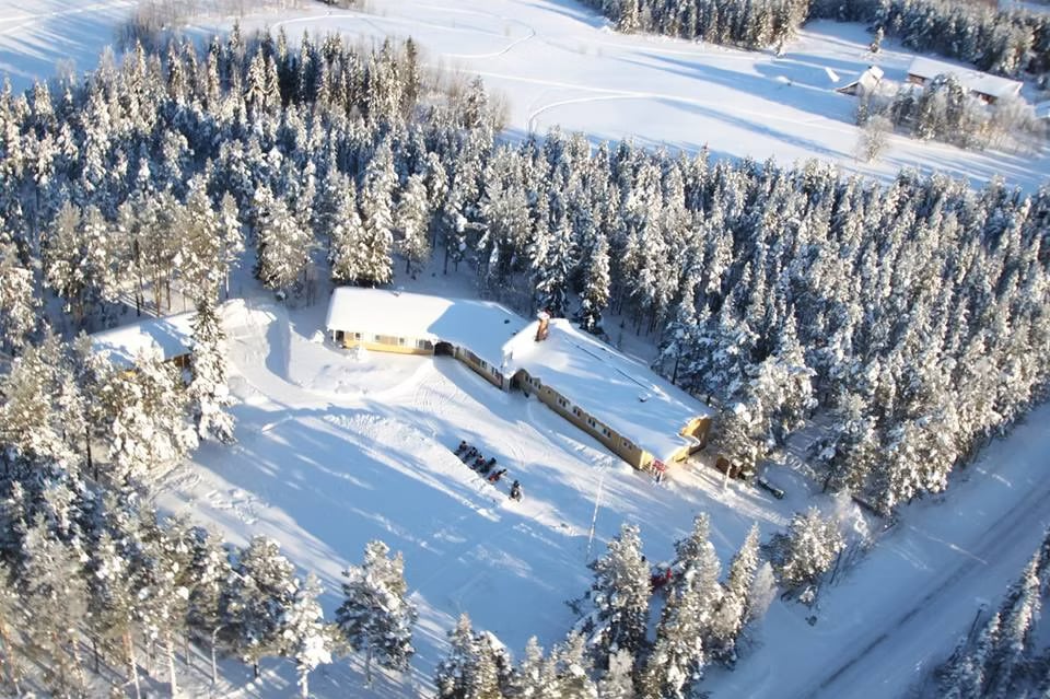 Aerial winter view of the Arctic Village surrounded by snow-covered forest near Levi, Finland.