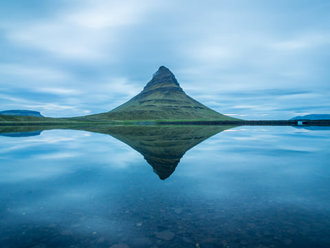 Enchanting view of Kirkjufell during dawn, reflecting in the water.