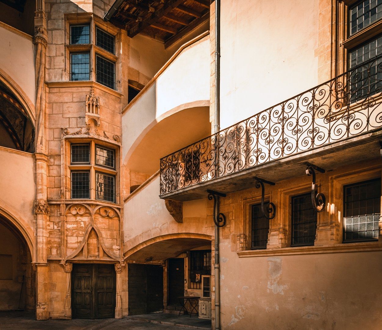 A picturesque Renaissance courtyard in Vieux Lyon, featuring elegant arches, intricate iron railings, and warm-toned historic architecture.