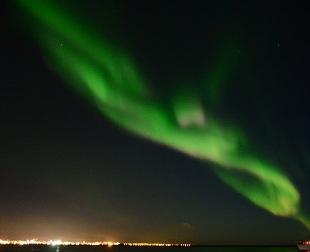 Boat guests watching the Northern Lights over the ocean