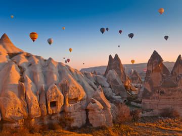 Cappadocia at sunrise — fairy chimneys under a sky filled with balloons.