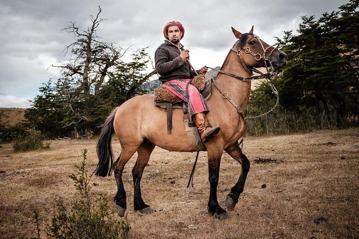 Argentinian gaucho poses on his horse bridled with an ornate harness.