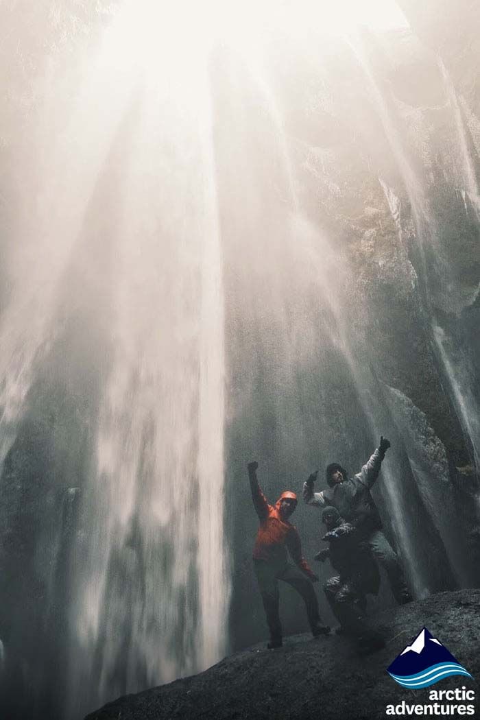 people excited under the waterfall during 2 day south coast tour Iceland