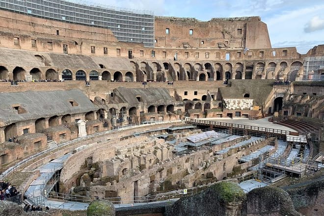 A sunset view of the arena and hypogeum surrounded by ancient high walls inside of the colosseum