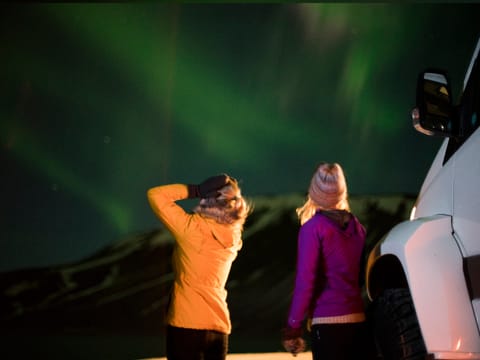 Women enjoying the Northern lights during Northern lights jeep tour in Iceland