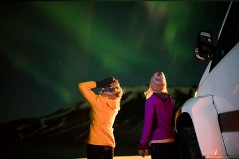 Women enjoying the Northern lights during Northern lights jeep tour in Iceland