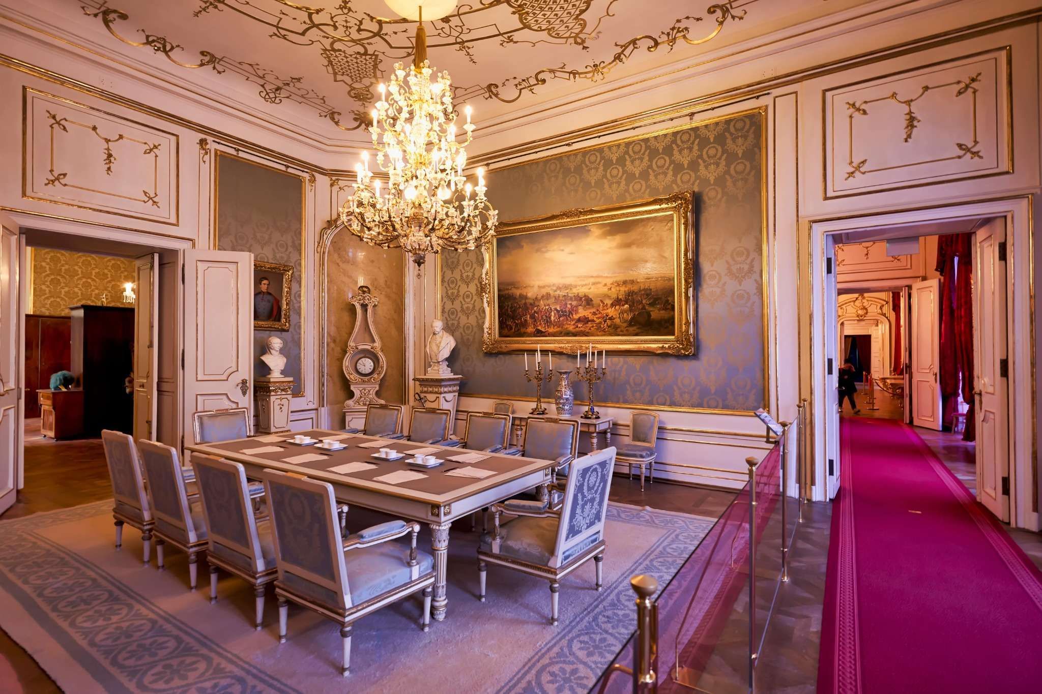 Ornate dining room with chandelier, long table, and classical decor at Sisi Museum