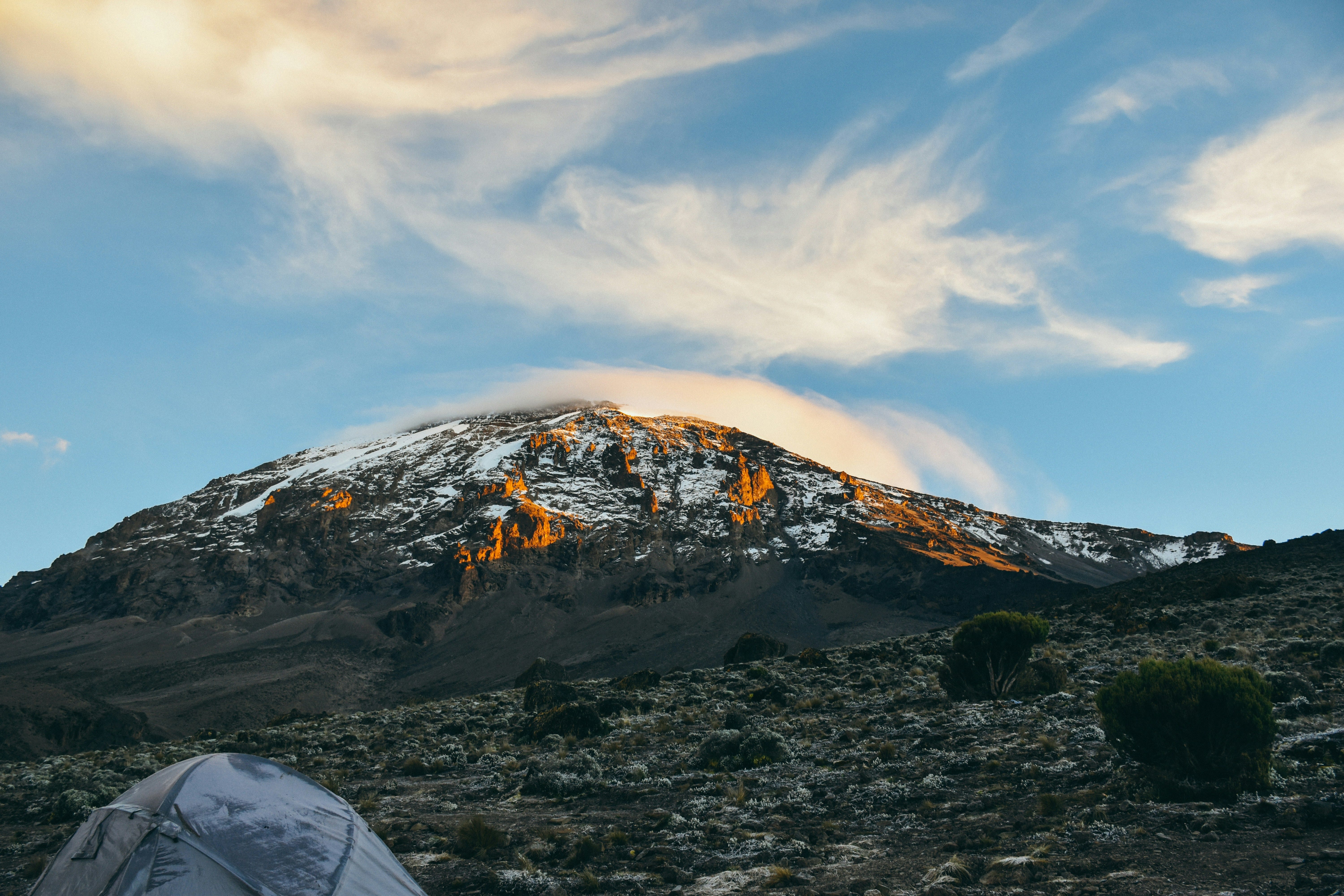 Panoramic view of the snow-capped Mount Kilimanjaro peak at sunrise during a luxury high-altitude mountain trekking expedition in Tanzania.