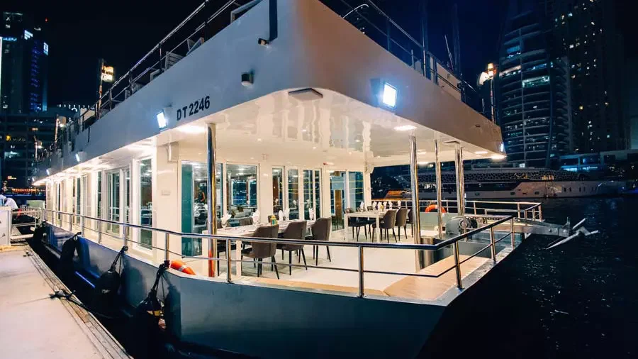 A brightly lit multi-level boat is moored at night with glass-enclosed dining areas at Alexandra Sea Lounge.