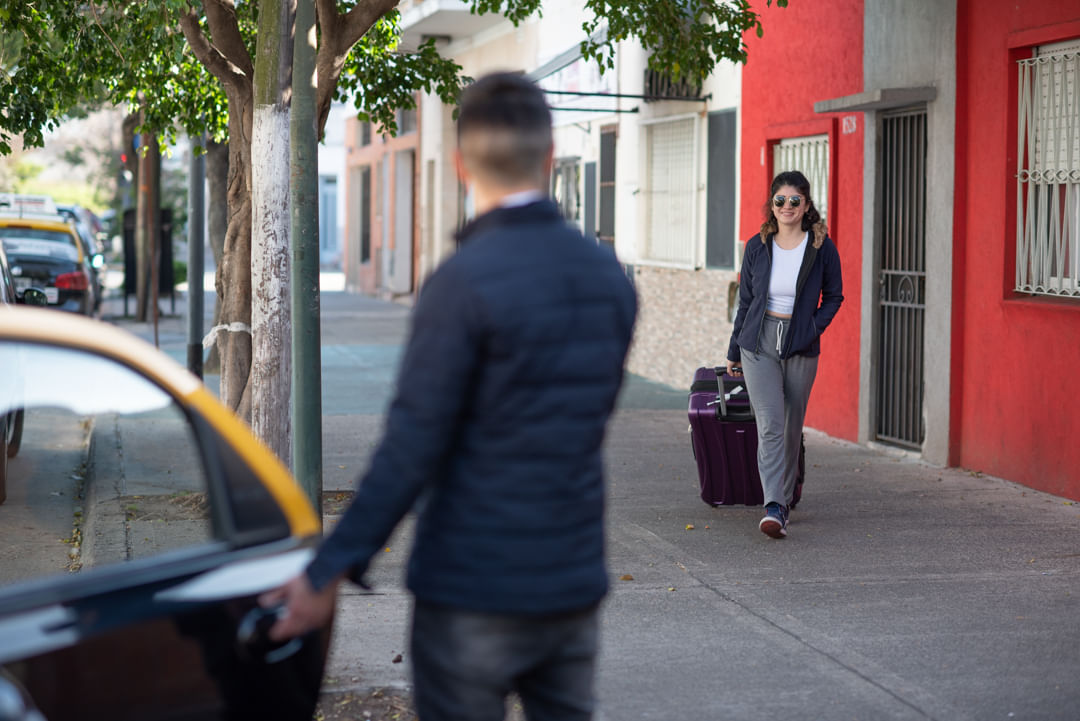 Driver assisting passenger with luggage outside hotel in Buenos Aires
