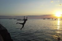 Boys jump to swim from Forodhani during high tide.