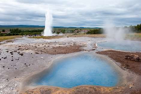 Blue hot spring with Geysir in distance