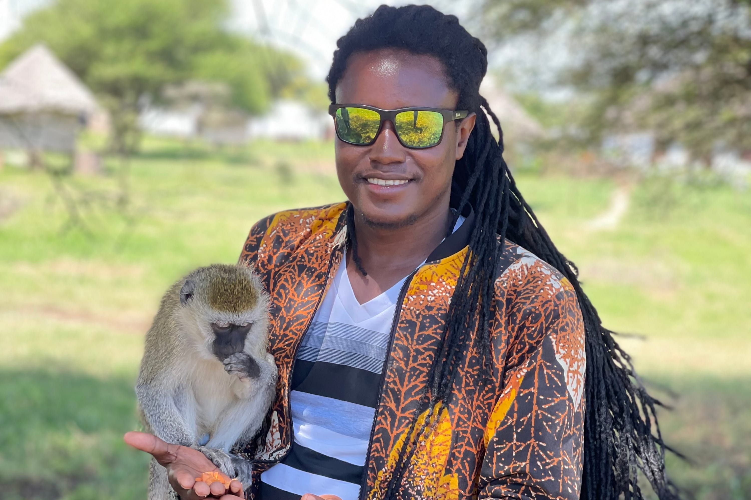 A professional guide holding a small monkey in a secure wildlife sanctuary.