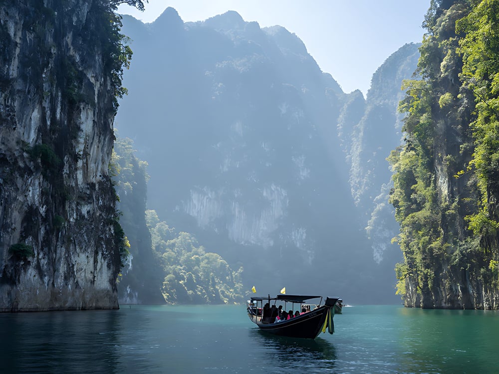 A longtail boat between towering limestone cliffs
