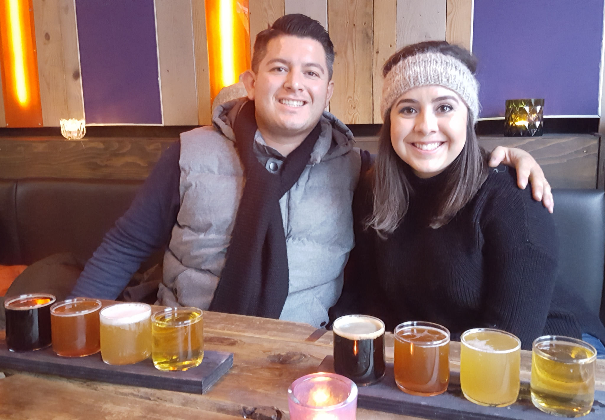A couple smiling while sampling different beers.