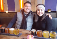 A couple smiling while sampling different beers.