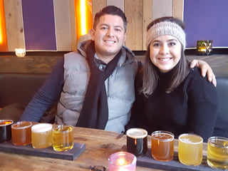 A couple smiling while sampling different beers.