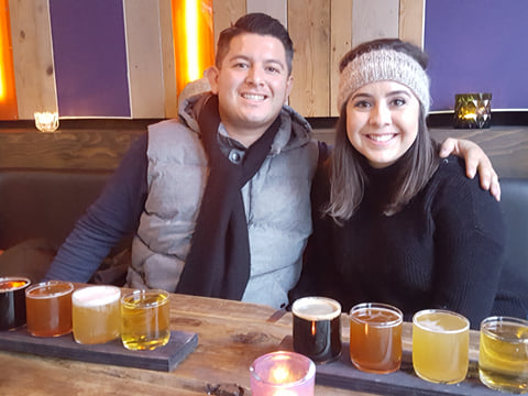 A couple smiling while sampling different beers.