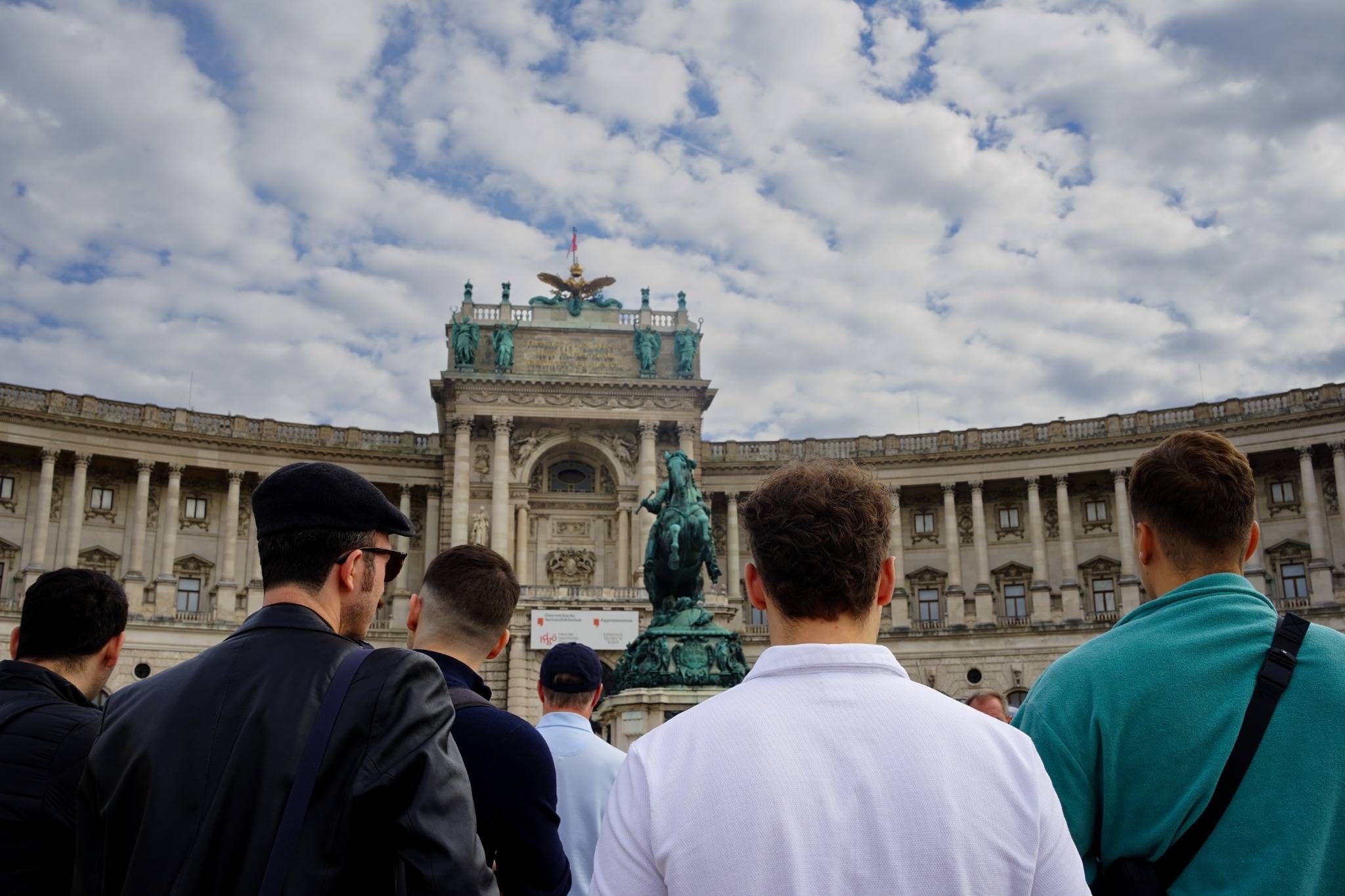 Group of people standing before the statue and grand facade of Neue Burg, Vienna