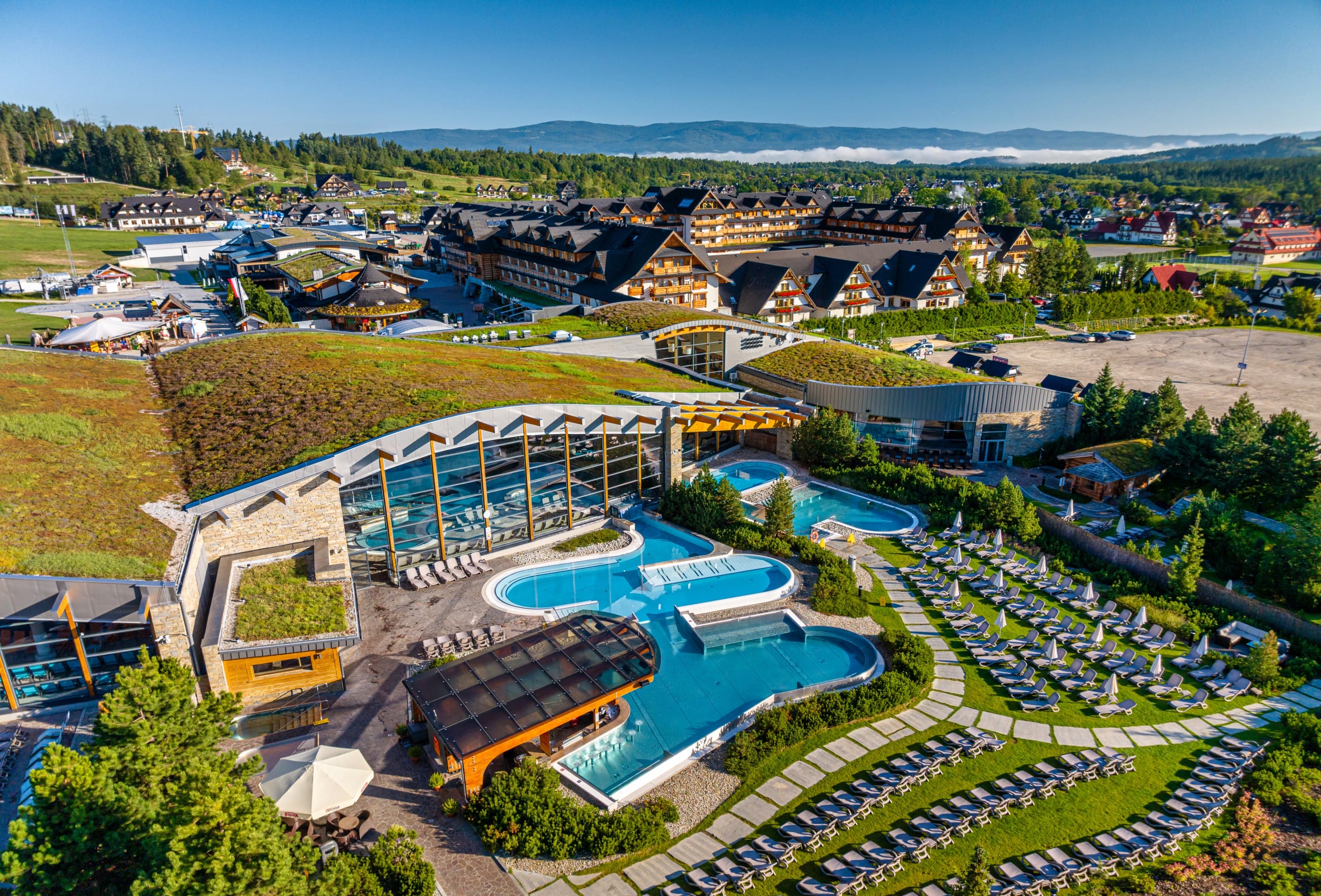 Aerial view of Terma Bania summer water park with colourful water slides, pools and hundreds of sun loungers