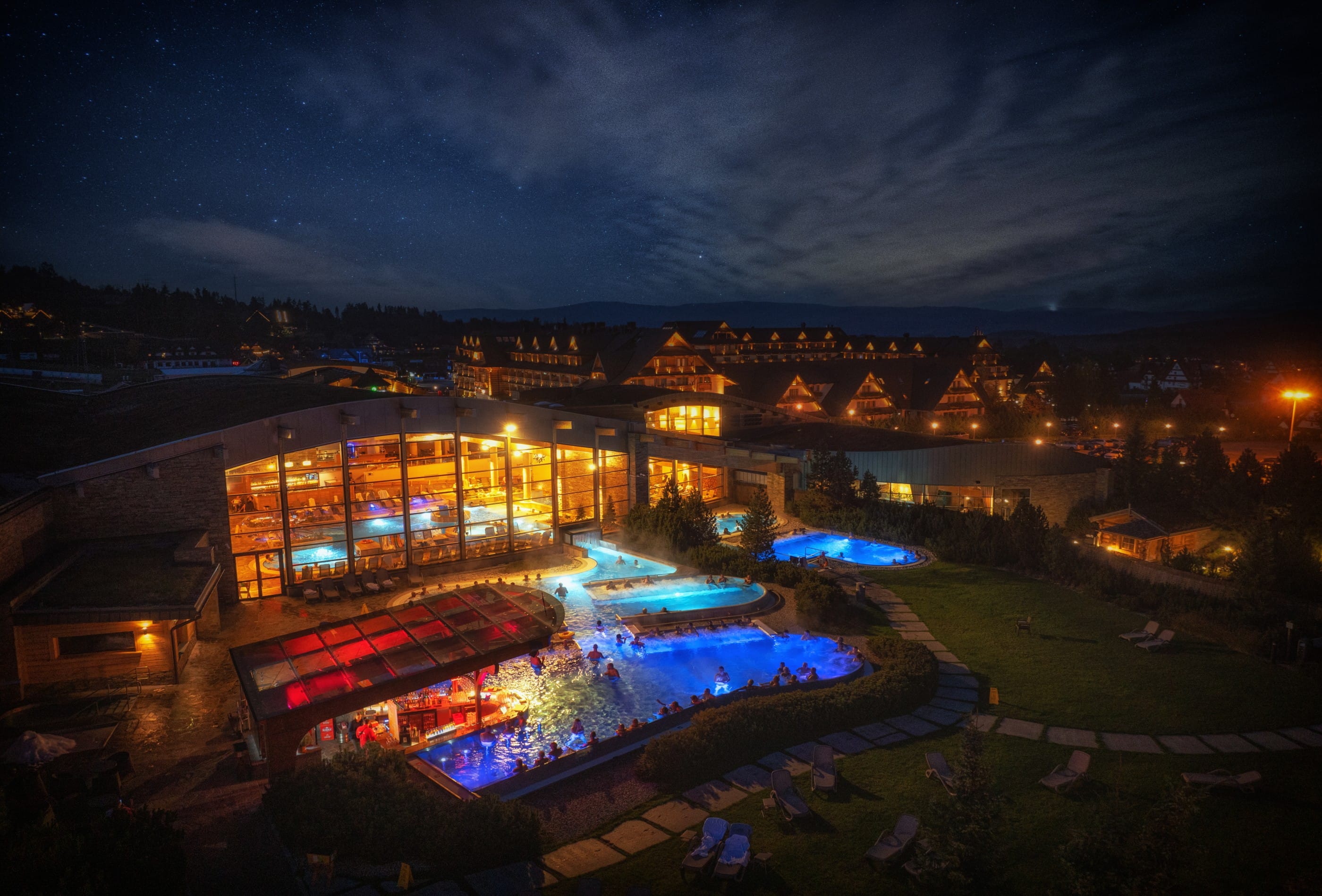 Terma Bania thermal complex illuminated at night with glowing outdoor pools and Podhale village lights