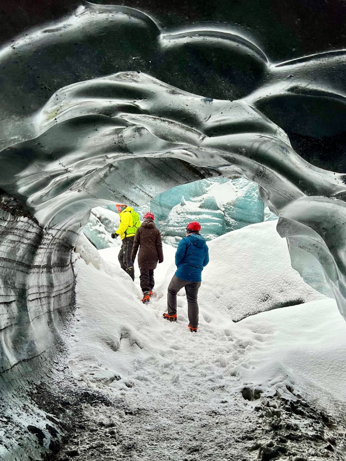 Two people and a guide walking around ice caves.