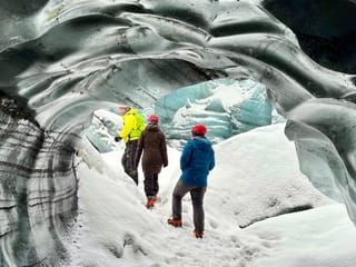 Two people and a guide walking around ice caves.