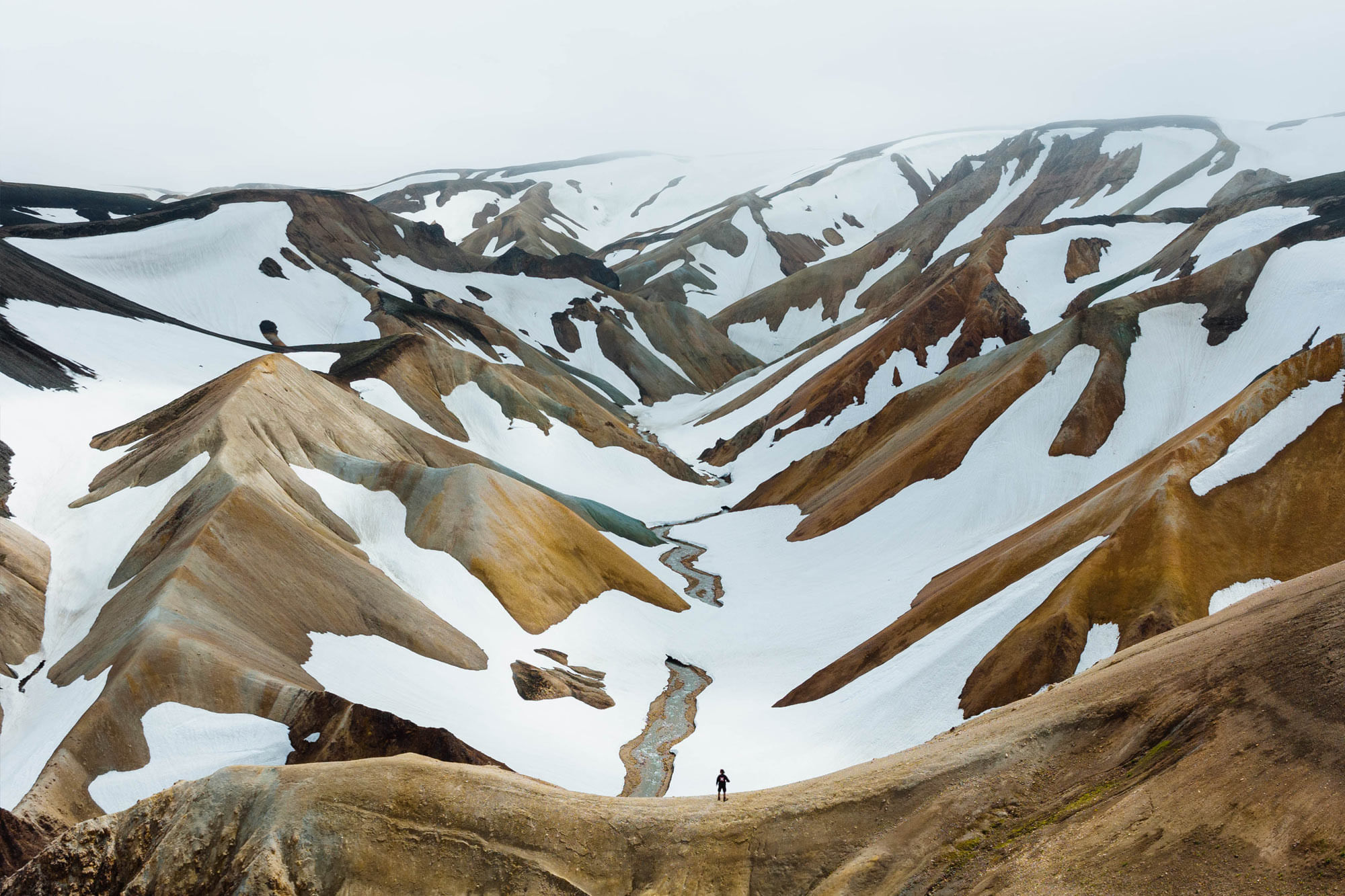 Man standing on a ridge looking over rhyolite mountains