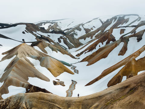 Man standing on a ridge looking over rhyolite mountains