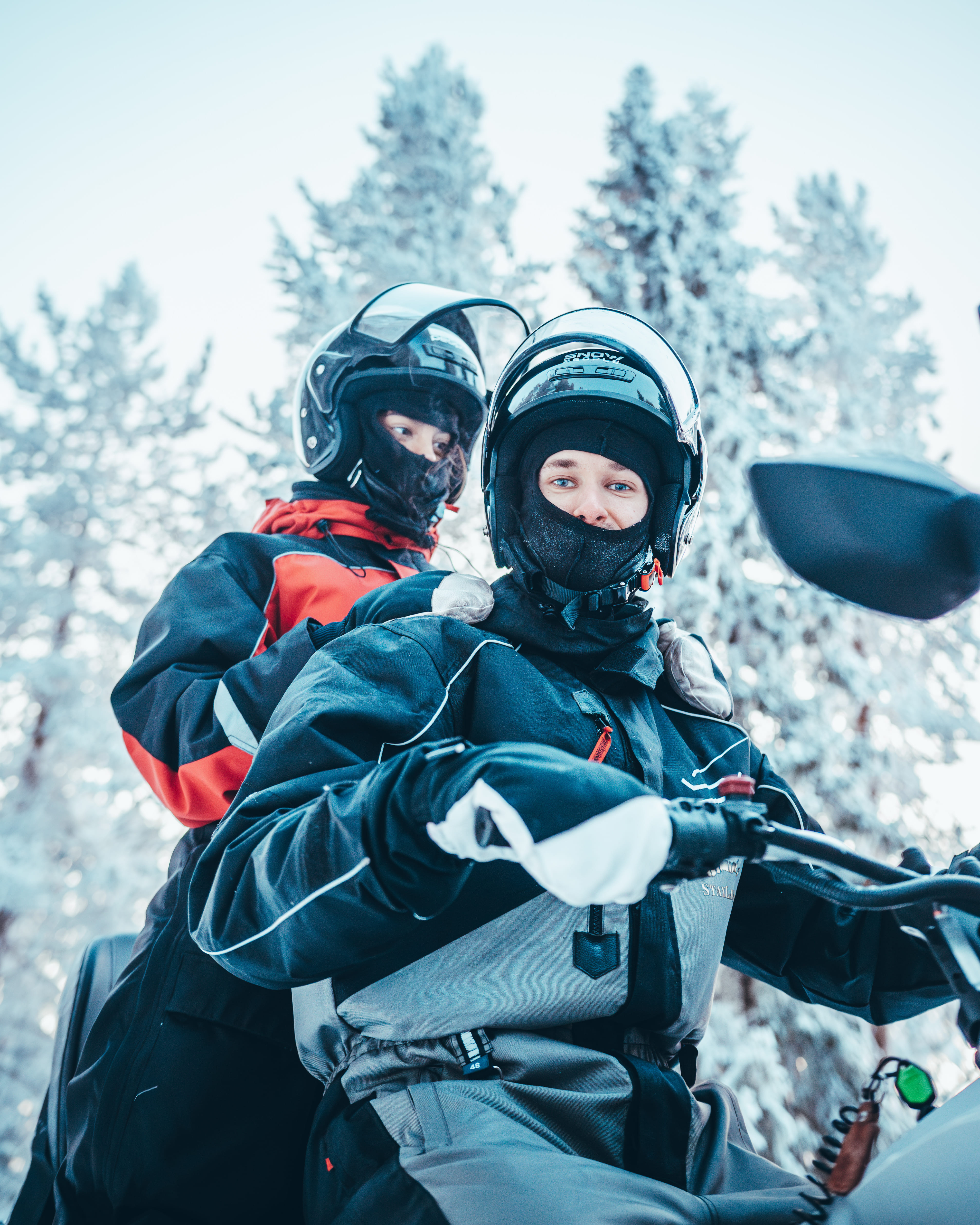 Two guests riding a snowmobile in the snowy landscape of Rovaniemi during StayLapland's Kuoksa Husky & Snowmobile Adventure.