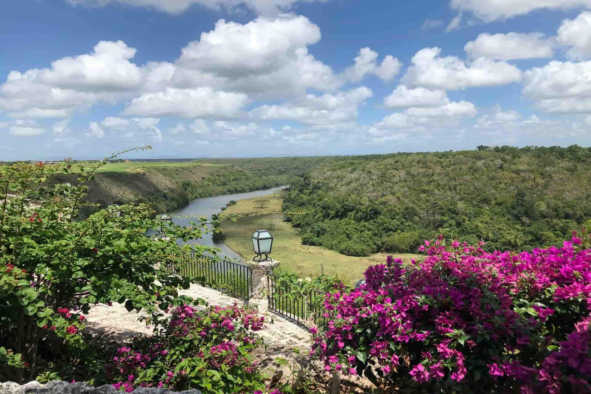 Buganvillas rosas en primer plano con vista panorámica al río Chavón desde Altos de Chavón, La Romana
