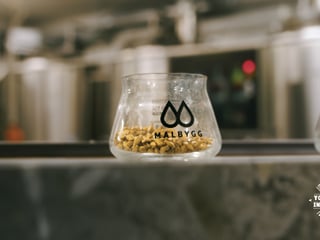 A glass with the malbygg logo on it