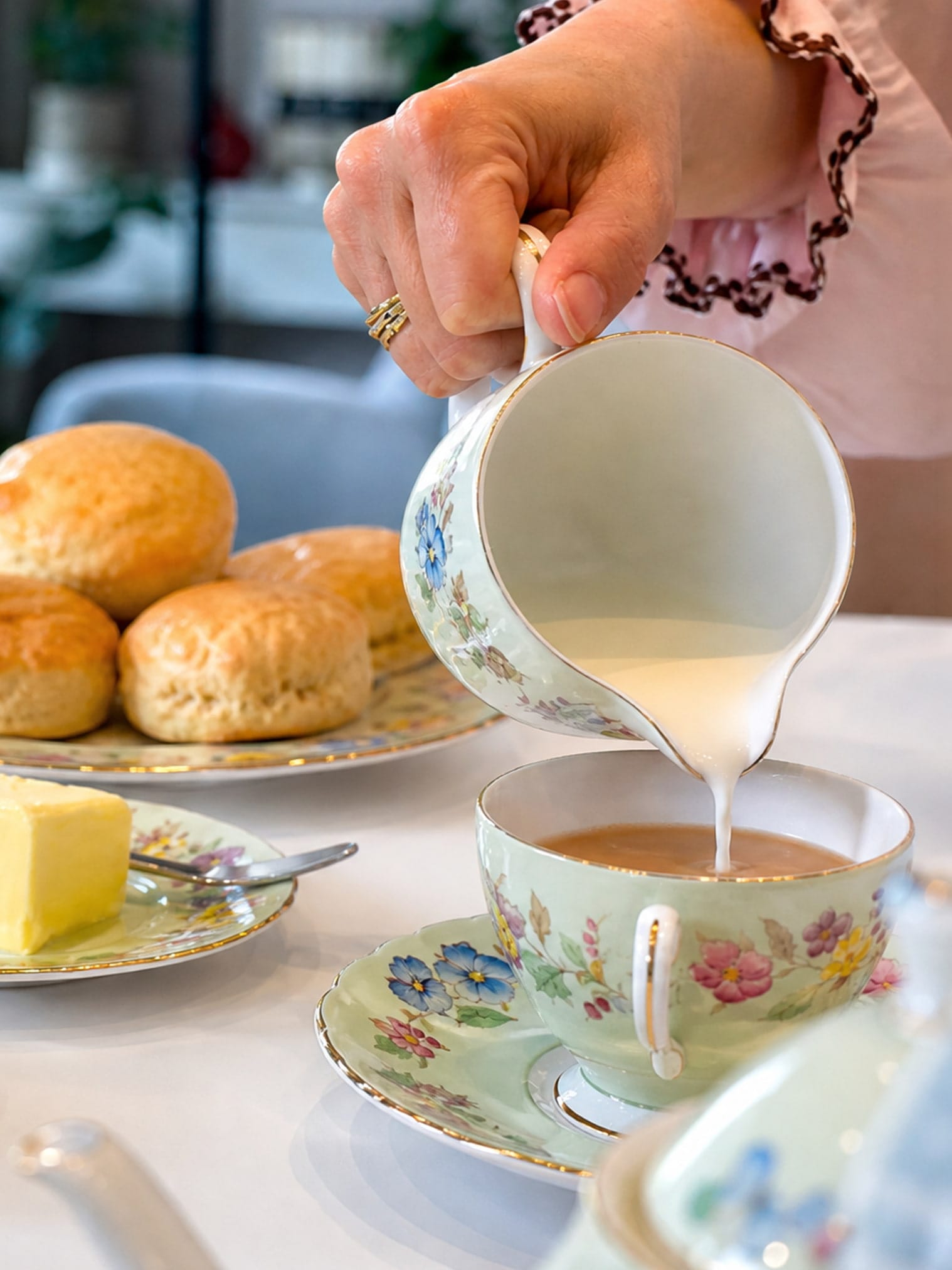 A milk jug pouring milk into a cup full of tea
