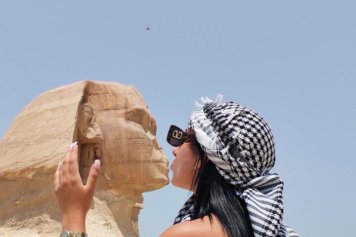 Tourist playfully posing as if kissing the Great Sphinx of Giza.