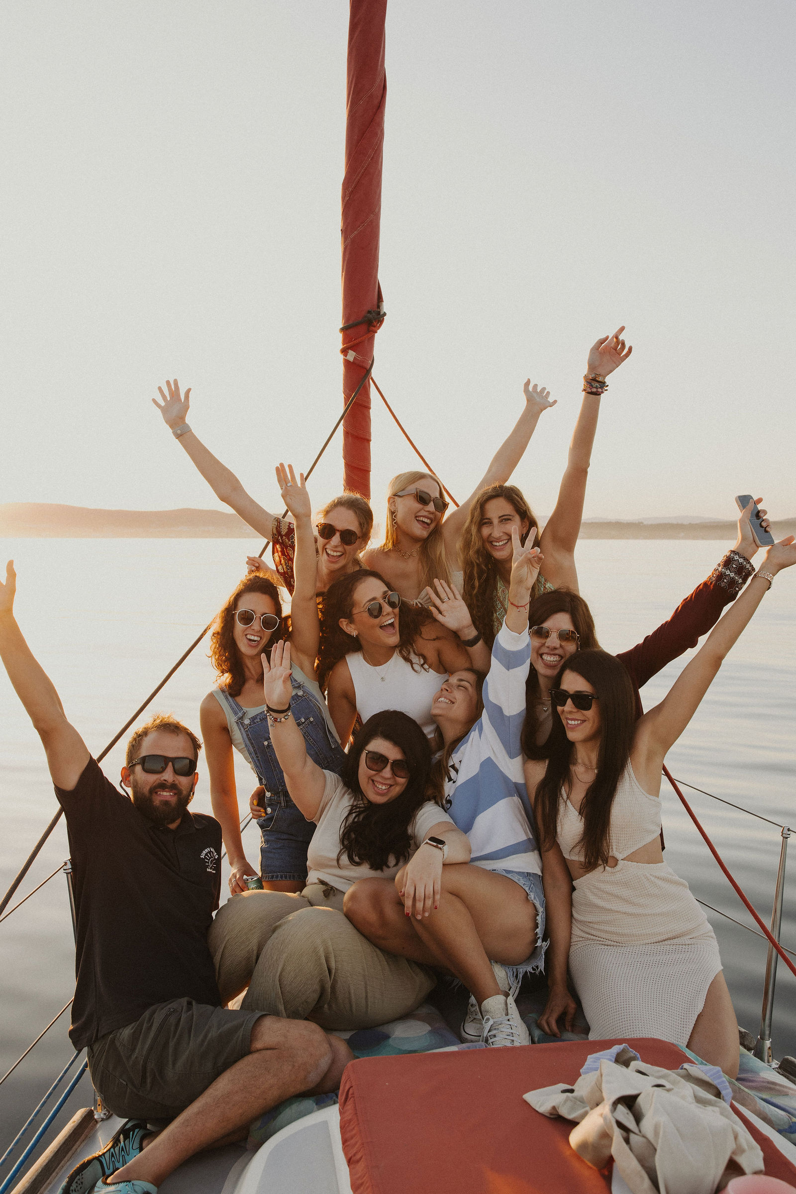 Grupo de amigos en Velero Assol en Sotogrande, Alquiler de velero privado al atardecer del velero rojo