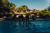 A group of four boys captured mid-motion as they fall into a swimming pool together.