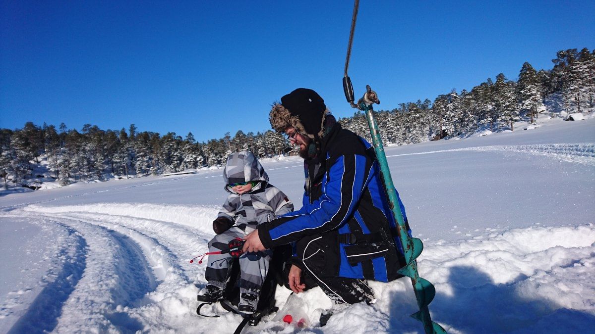 A father and his son ice fishing in Lake Inari.