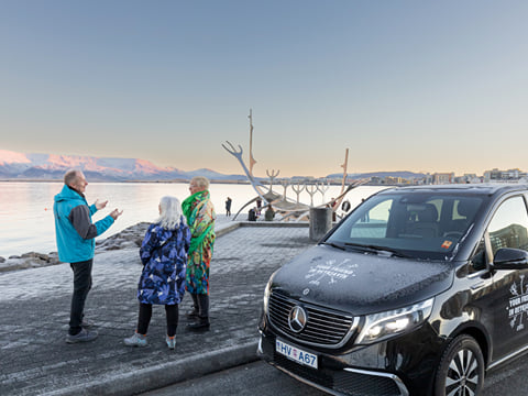 A group of travellers listening to a story by the Sun Voyager in Reykjavik.