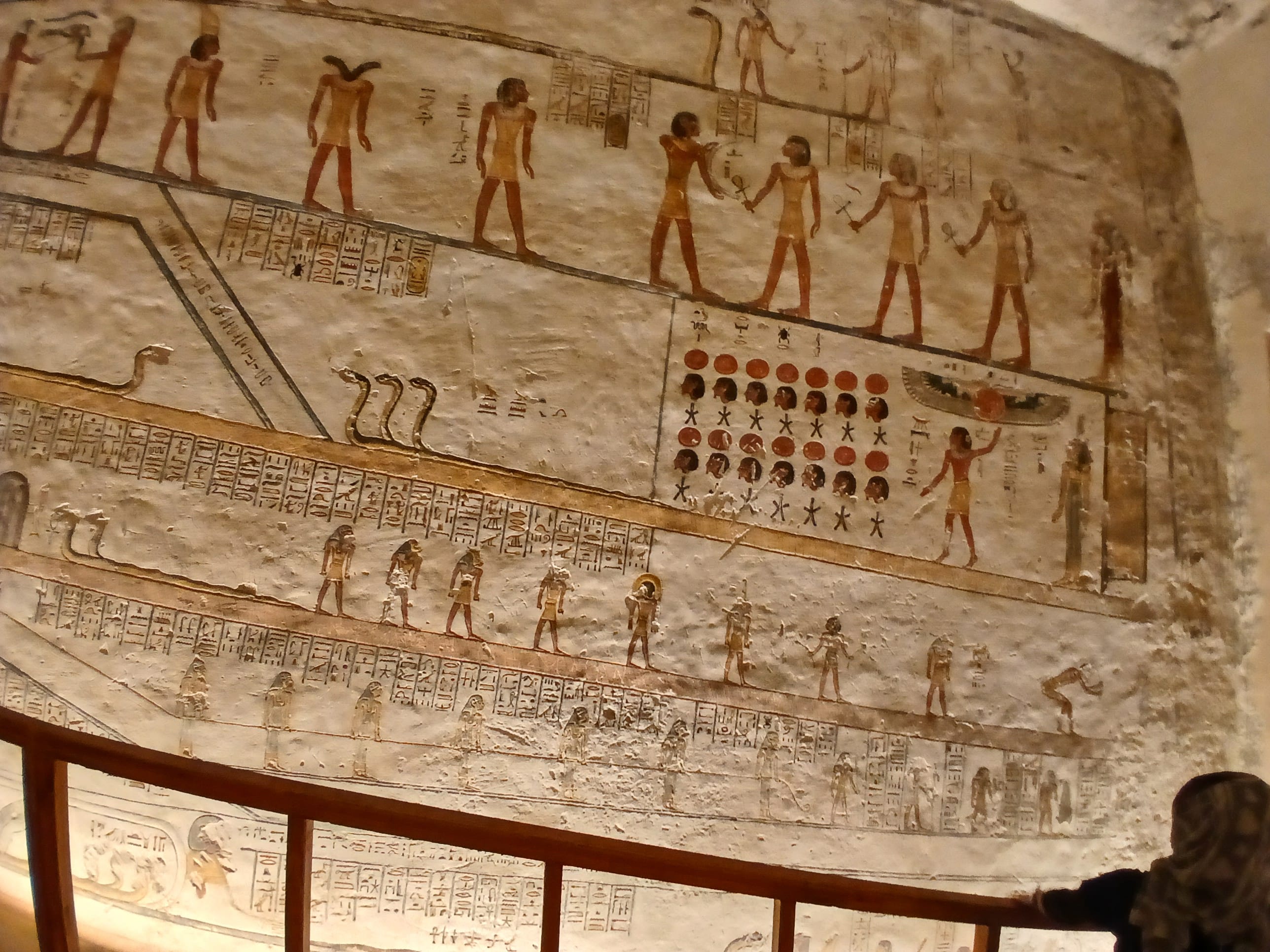 A close-up view of a beige stone wall with colorful, finely carved Ancient Egyptian hieroglyphs and deities inside the tomb of Merenptah 