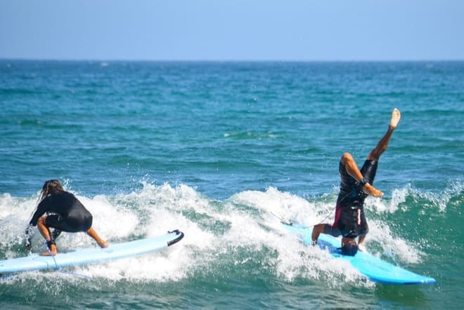 Surfers falling off surfboards during a fun beginner surf lesson in Los Cabos