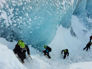 People climing out of a large crevasse