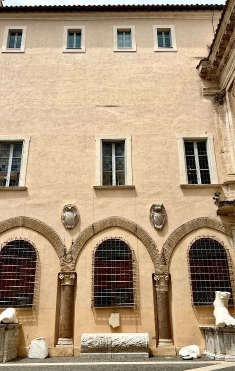 Sunlit façade with arched windows and sculpted medallions in the Capitoline Museums complex.