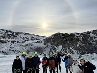 People standing on a glacier with a solar halo behind