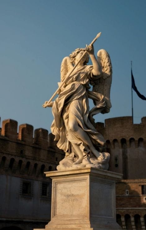 Marble Archangel Michael statue by Raffaello da Montelupo in Castel Sant’Angelo, Rome, set against a blue sky.